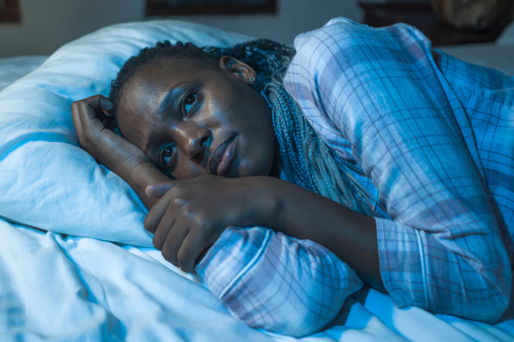 Woman lays awake in bed unable to fall asleep.