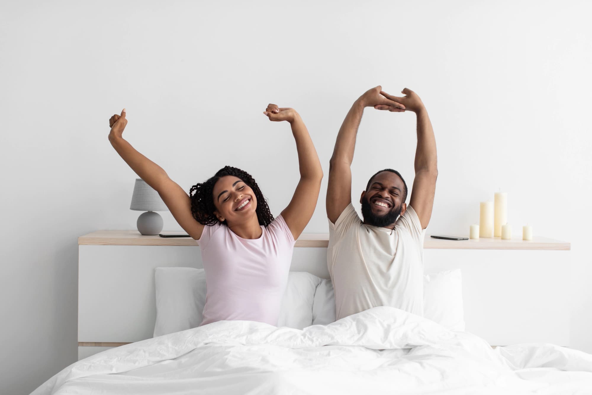 Young couple waking up stretching in bed.