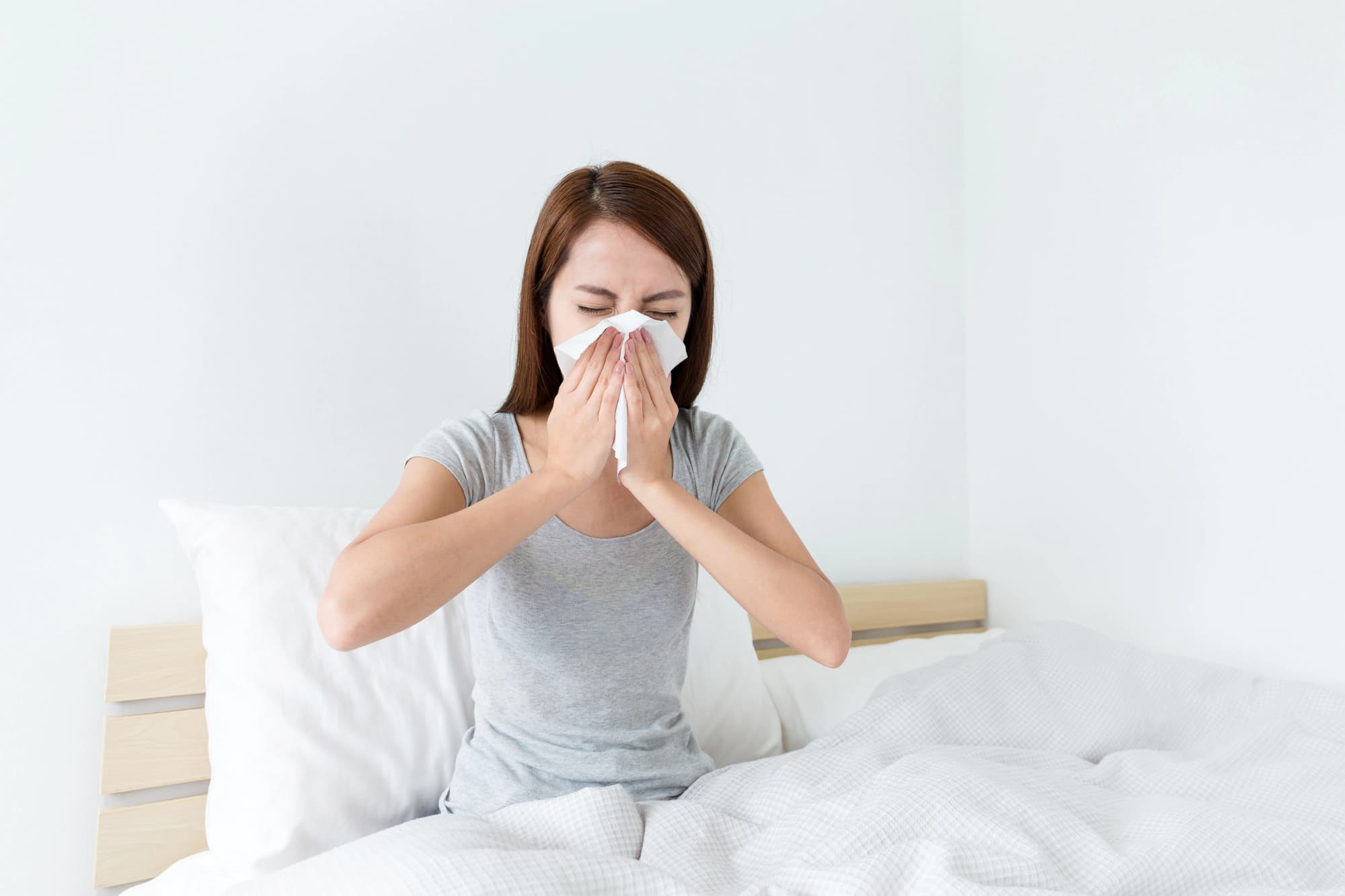 Woman blowing her nose in bed.