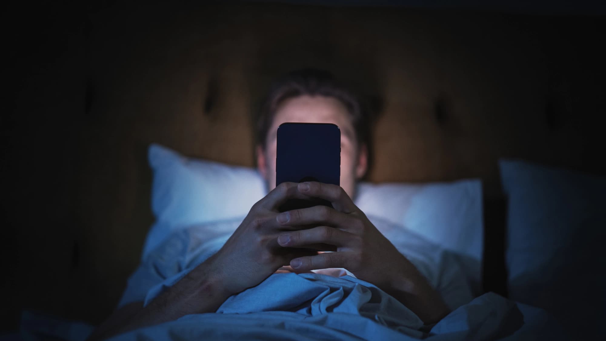 Man using smartphone in bed.