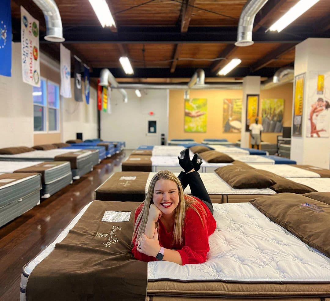 Woman sitting on bed in Texas Mattress Makers showroom.