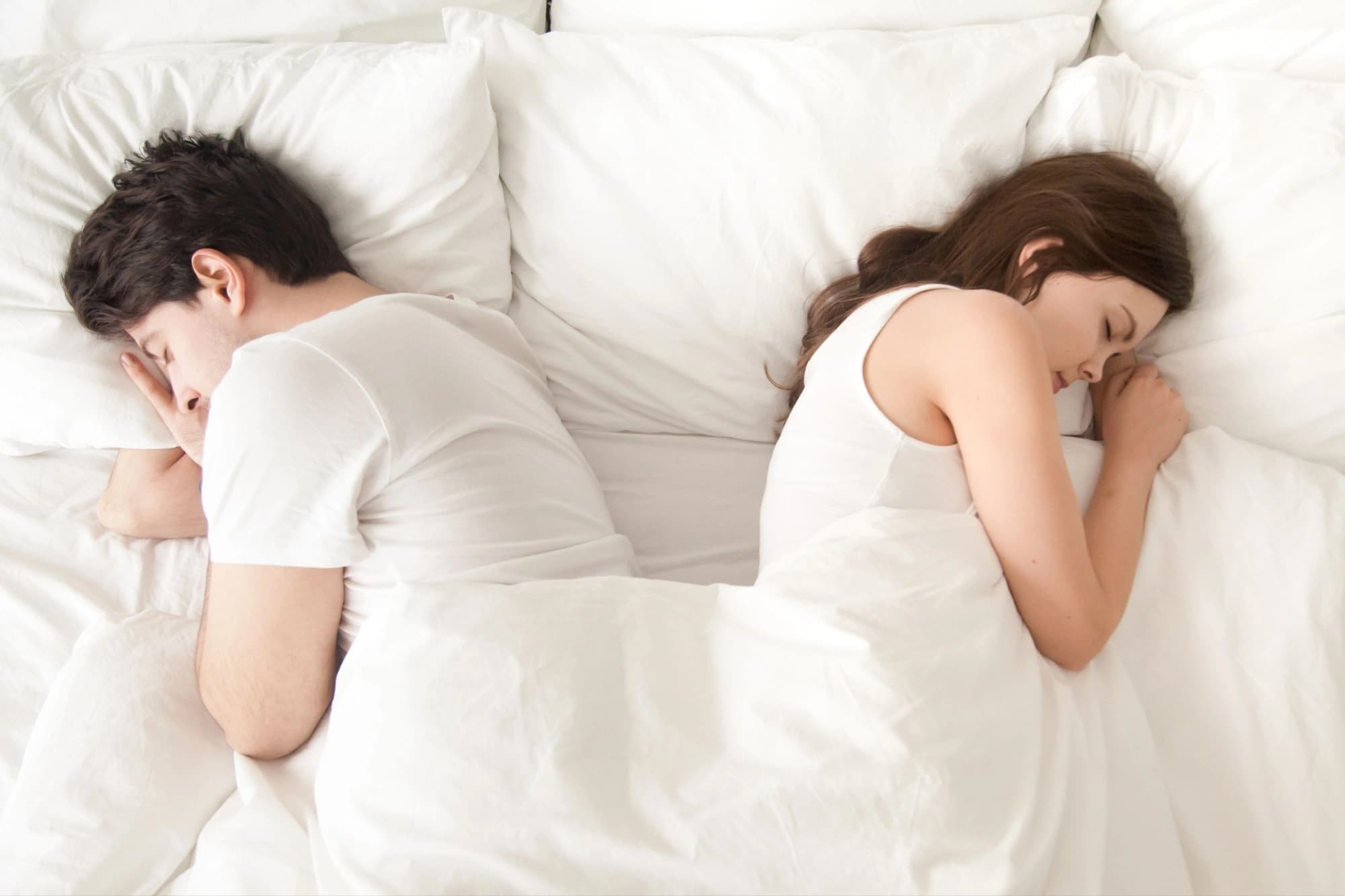 Man and woman sleeping separately back to back in bed