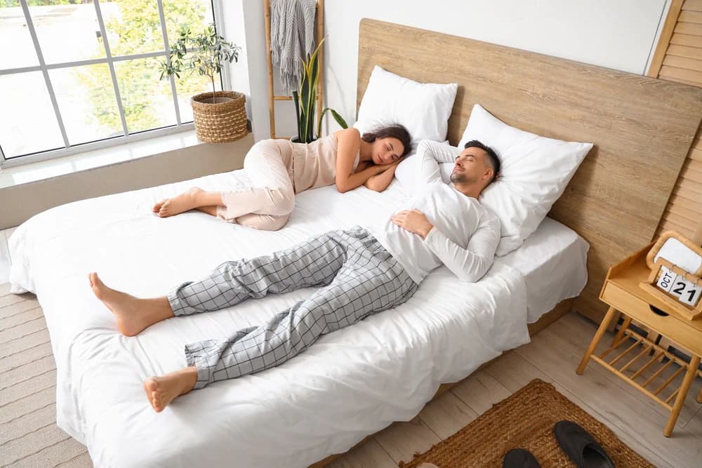 Couple asleep on their split king bed