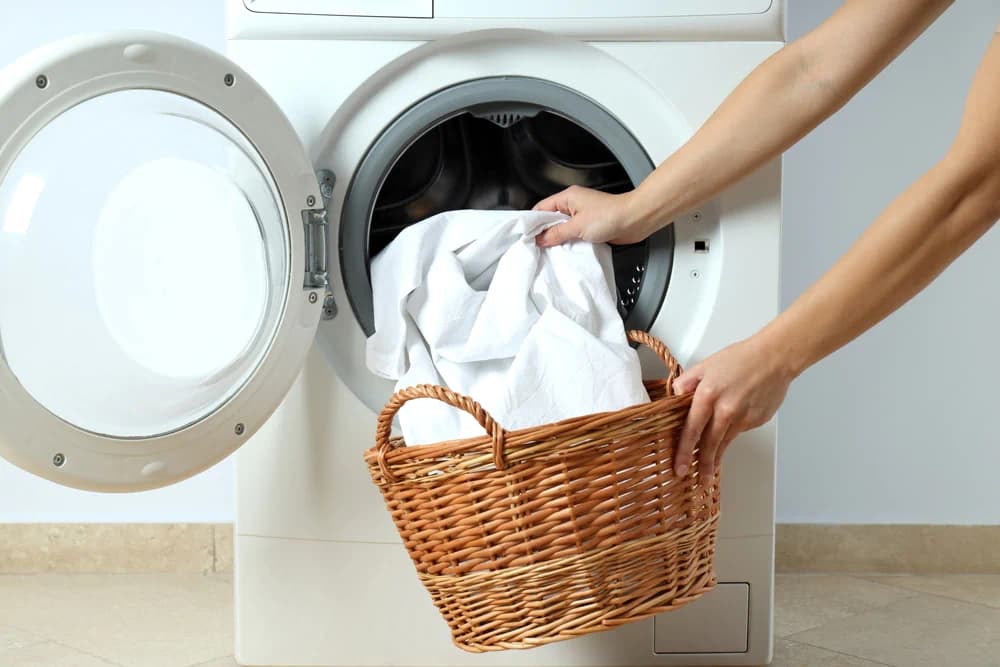 Someone pulling their mattress protector out of the washing machine