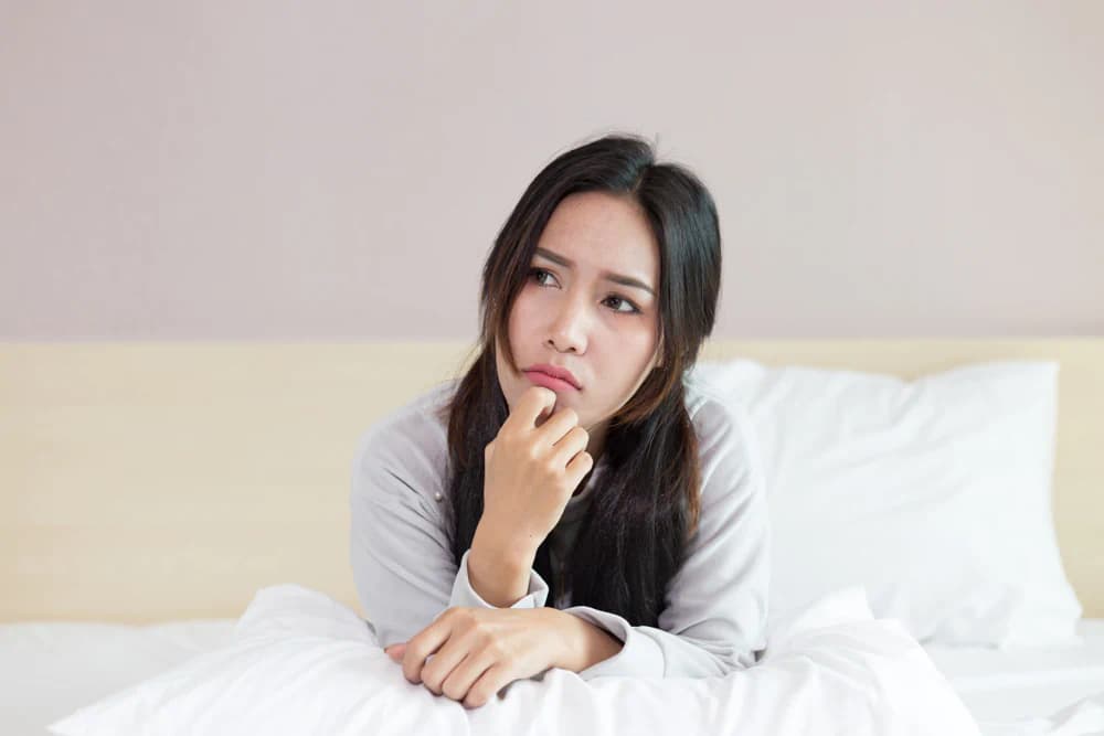 Confused woman sitting in bed