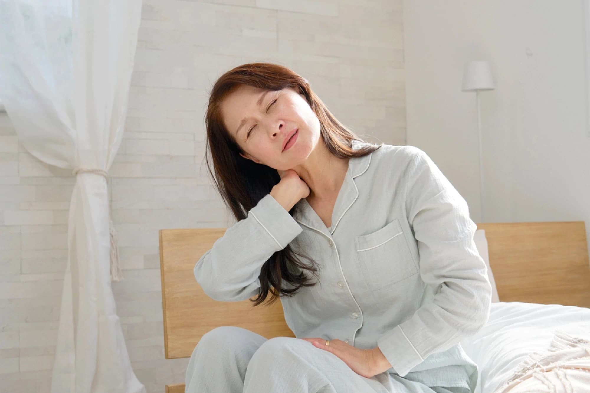 Older Asian woman waking up with neck pain