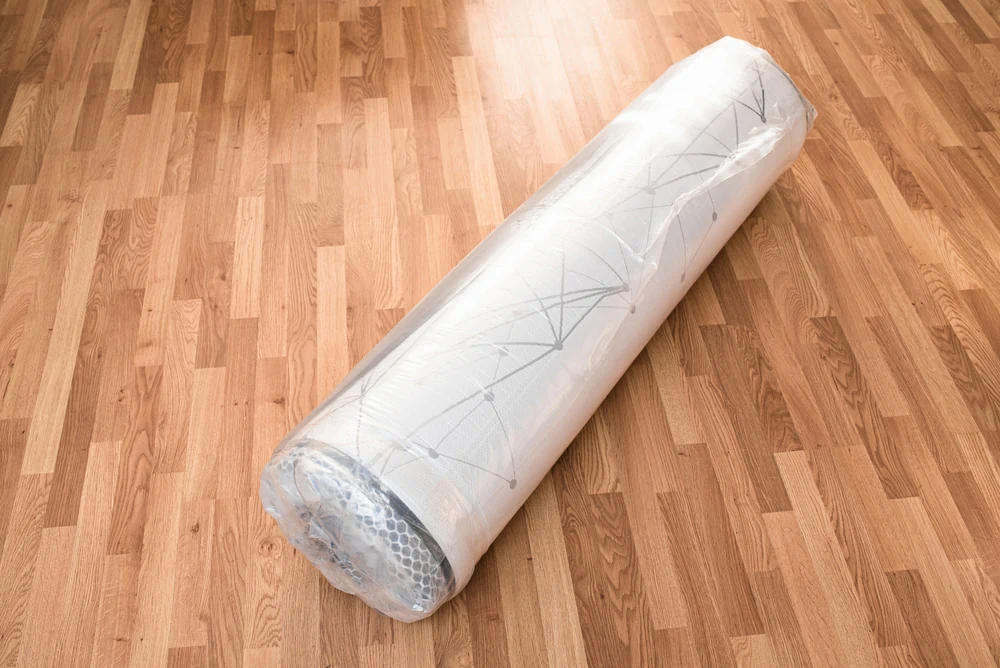 A mattress rolled up and packaged on the floor