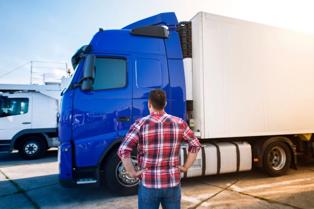 Man standing in front of blue and white 18-wheeler semi-truck.