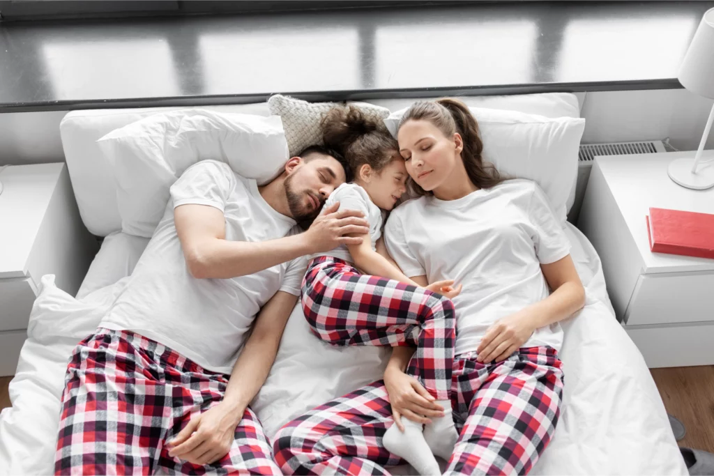 Mom, dad, and daughter asleep wearing matching pajamas.