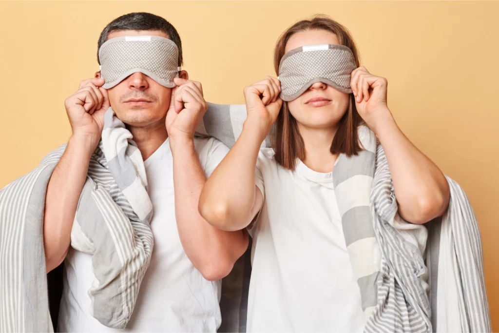 Man and woman wearing sleep eye masks.